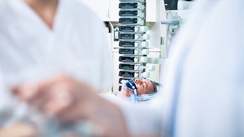 Patient liegt auf Intensivstation – viele B. Braun Infusionspumpen im Hintergrund