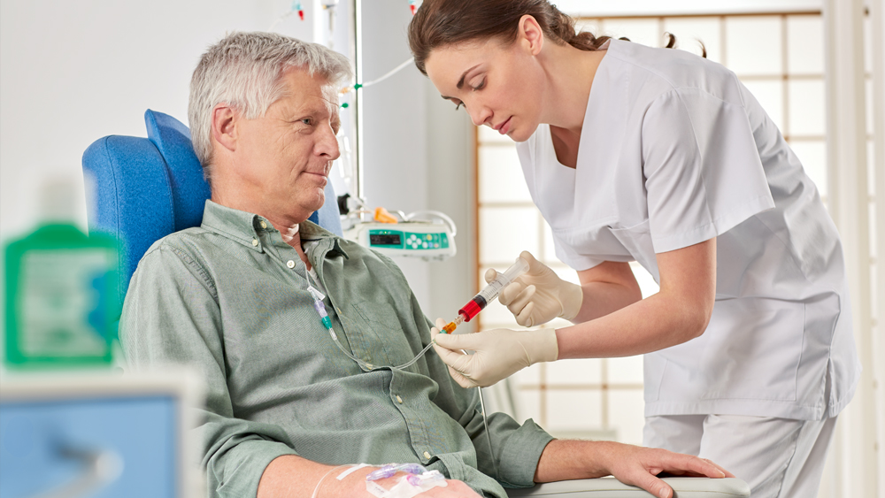 Die Pflegekraft gibt dem sitzenden Patienten Medikamente über eine Spritze