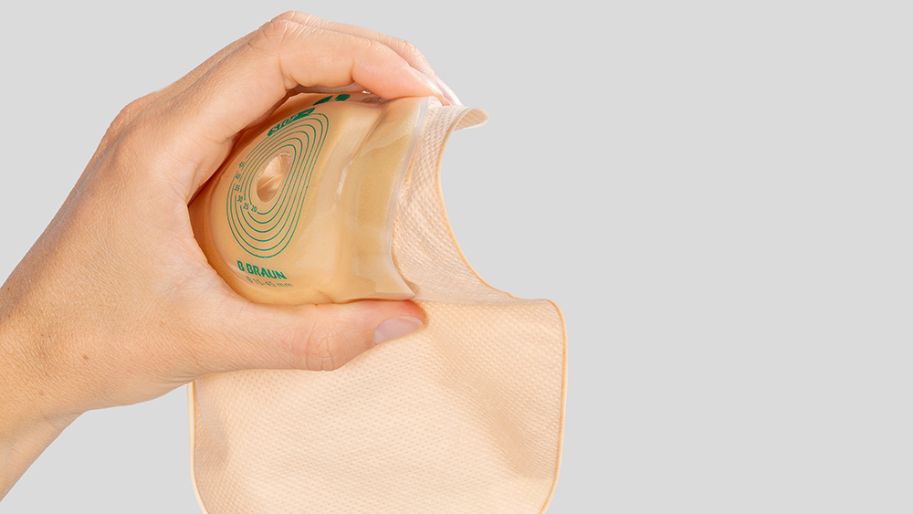 Main tenant une poche de stomie