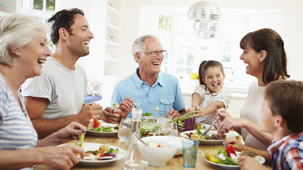 Une famille assise à table mangeant et riant