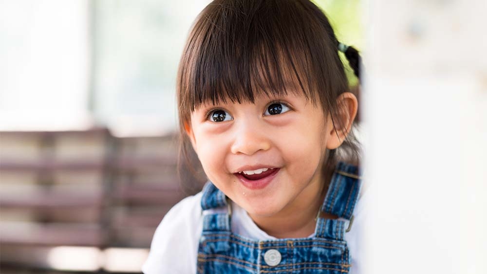 Un petit enfant joyeux se lève, son sourire rayonnant de bonheur et d’innocence. 