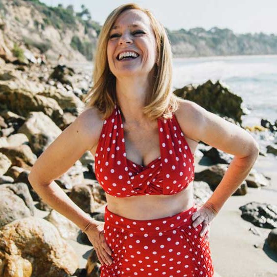 femme à la plage riant en bikini rouge à pois blancs